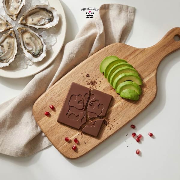 A flat lay composition of oysters, dark chocolate, and avocados on a rustic table, showcasing the best food for sex stamina.