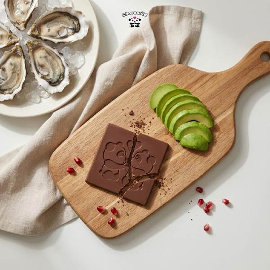 A flat lay composition of oysters, dark chocolate, and avocados on a rustic table, showcasing the best food for sex stamina.